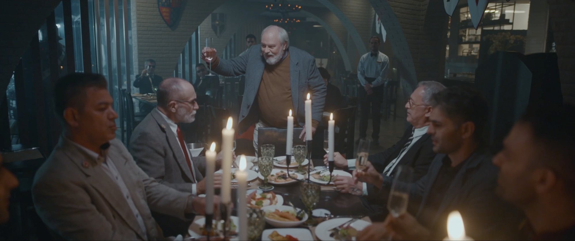 Candlelit dinner scene with guests at a long table