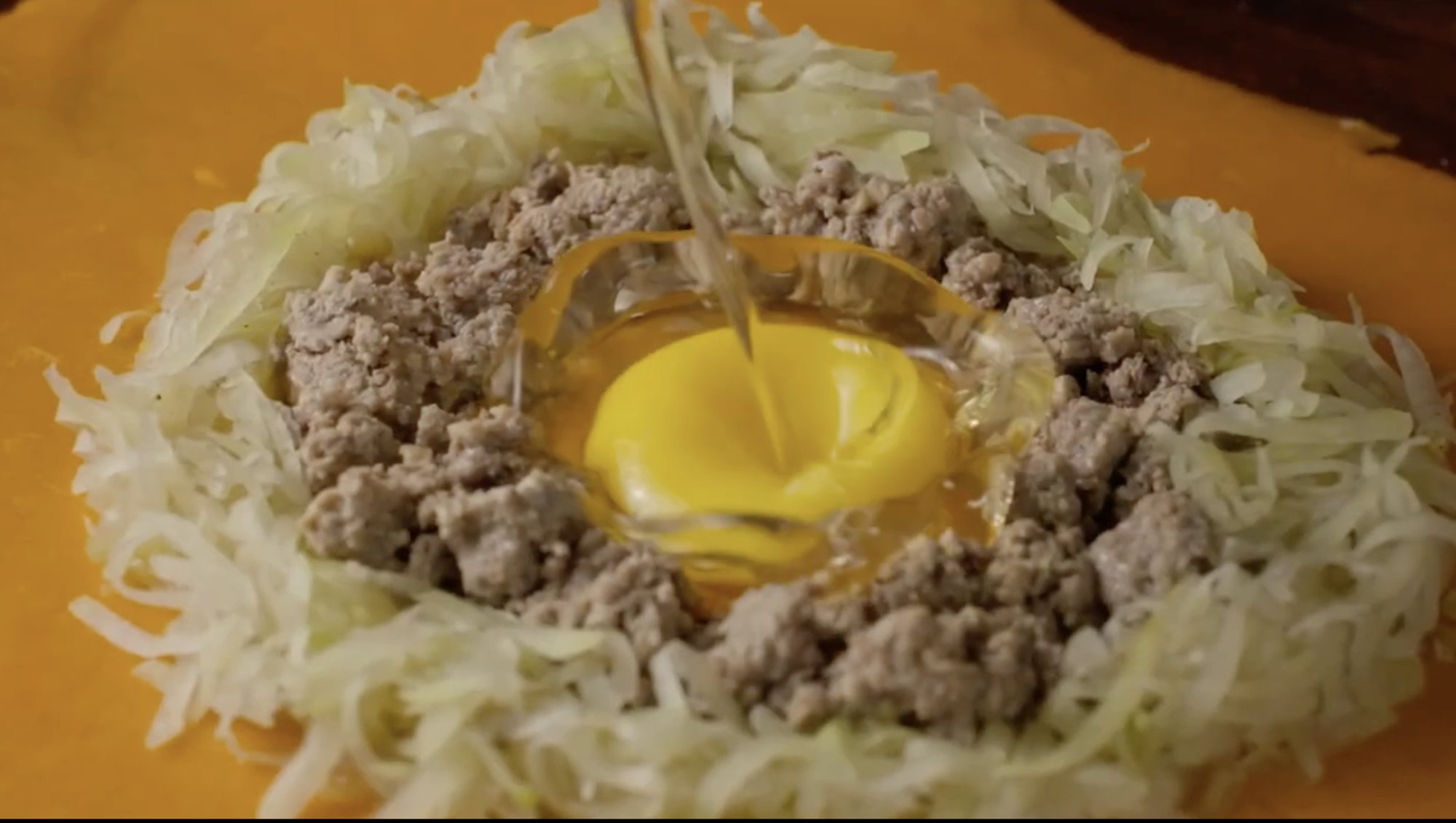 Egg yolk poured into a nest of ground meat