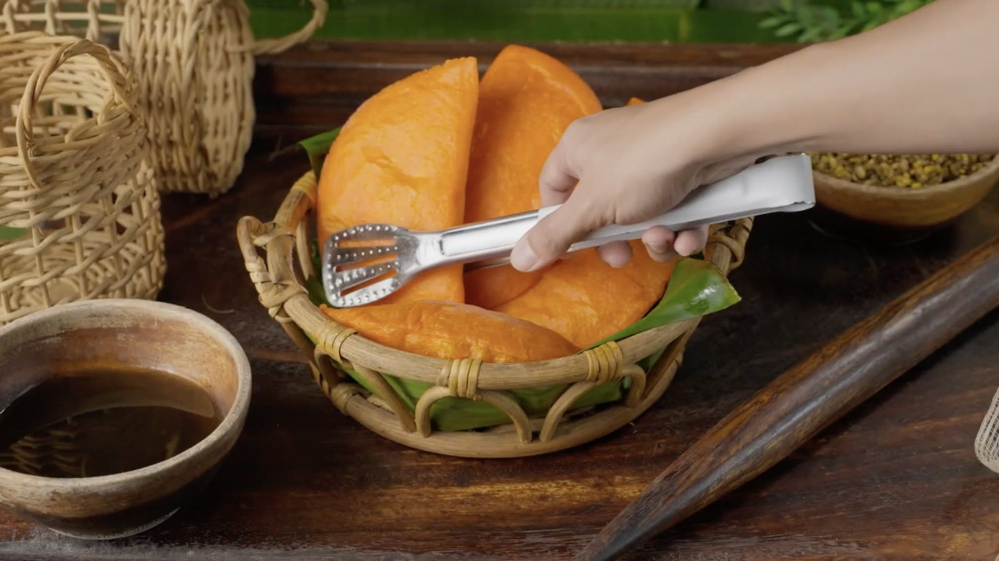Empanadas lifted with tongs from a woven basket