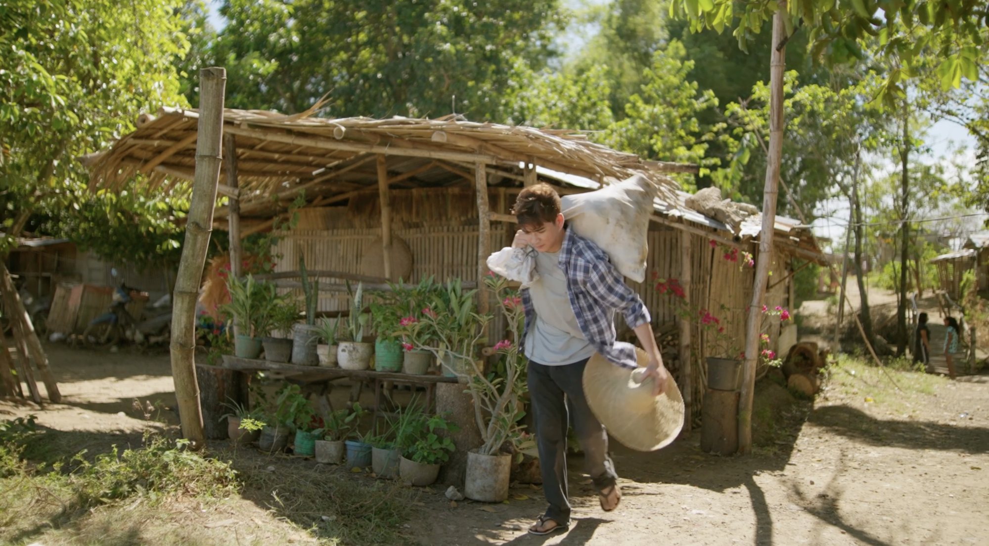 Farmer carrying a sack past a rural hut