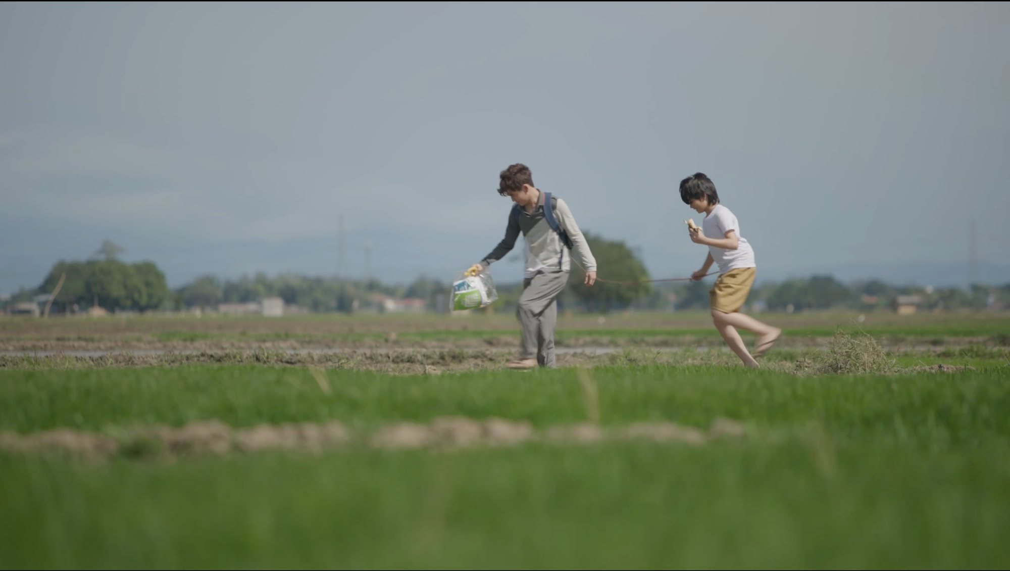 Two children running across a rice field