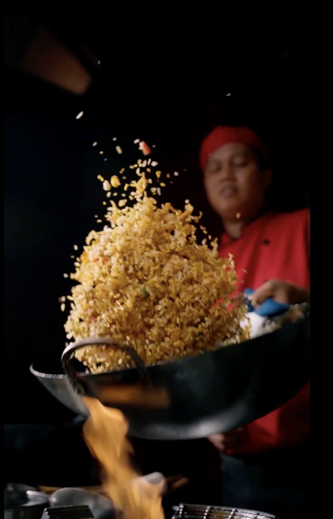 Chef tossing fried rice over a flaming wok